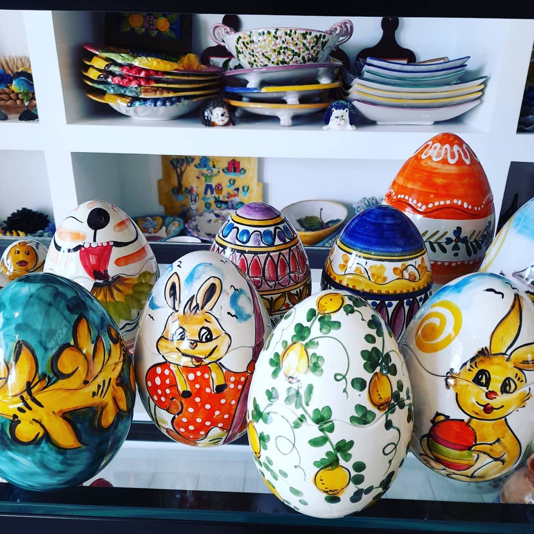 Uova di Pasqua colorate e decorative con disegni dipinti a mano e piatti su una mensola sullo sfondo.