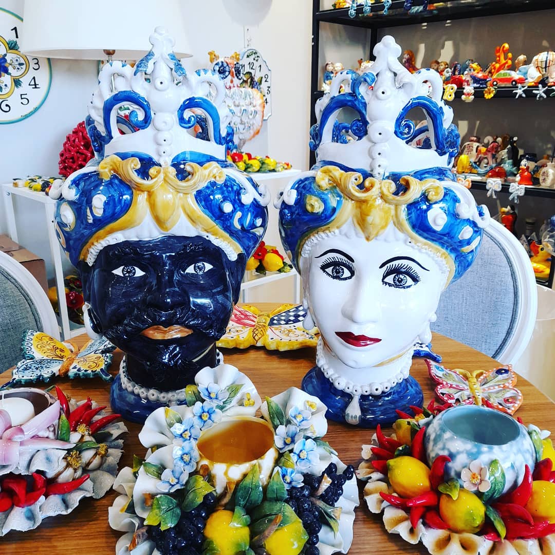 Teste in ceramica, una nera e una bianca, con corone. Apparecchio da tavola decorativo con altre ceramiche.