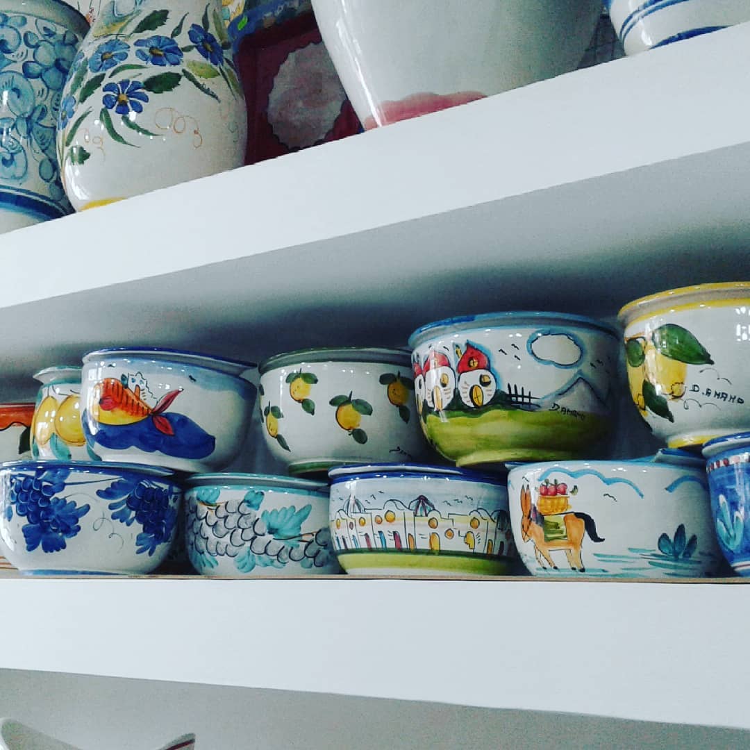 Scaffali pieni di ciotole e vasi in ceramica colorati e dipinti a mano, con vari motivi.