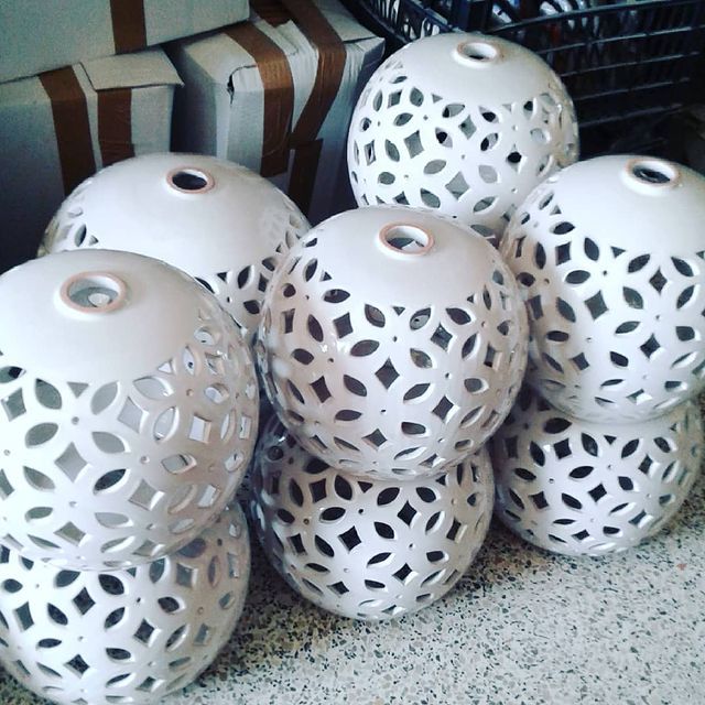 Sfere in ceramica bianca con motivi traforati, impilate insieme.