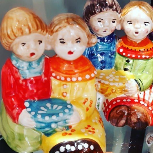 Figure di bambini in ceramica: due con i capelli biondi, uno con una ciotola in mano, gli altri con abiti colorati ed espressioni neutre.