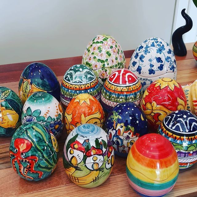 Assortimento di uova di Pasqua in ceramica colorate e dipinte a mano su un tavolo di legno.