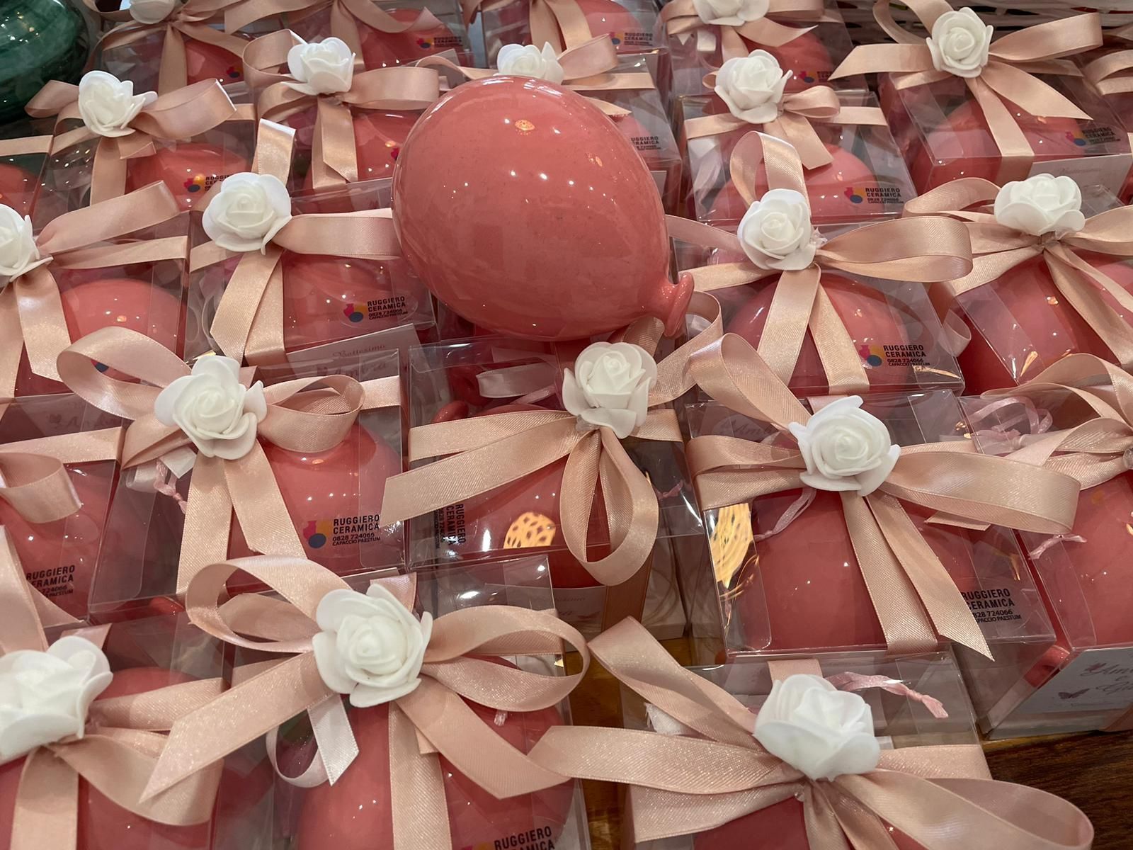 Regali rosa in scatole trasparenti, legati con nastri e decorazioni floreali.