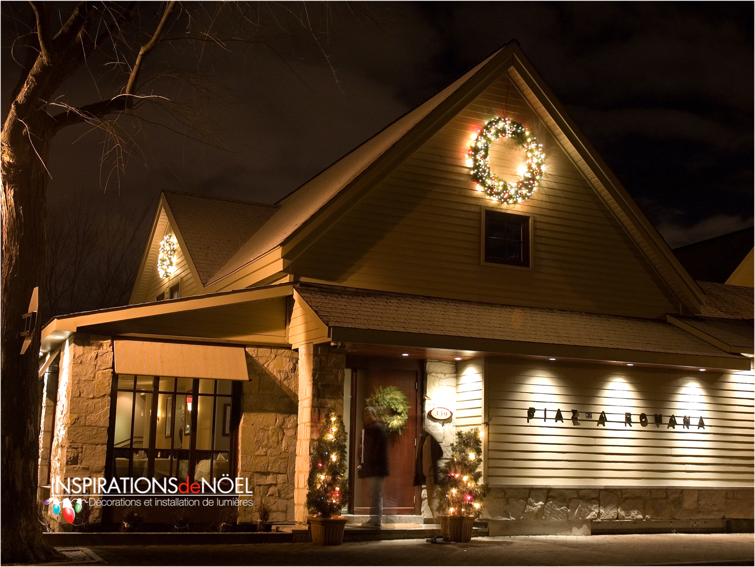 A christmas wreath hangs from the roof of a building