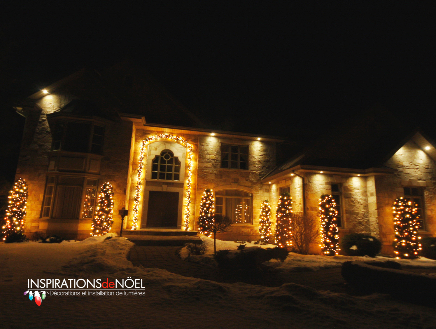 A large house is decorated with christmas lights at night