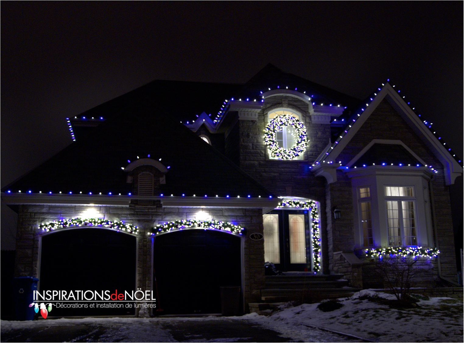A house is decorated with blue lights and a wreath in the window