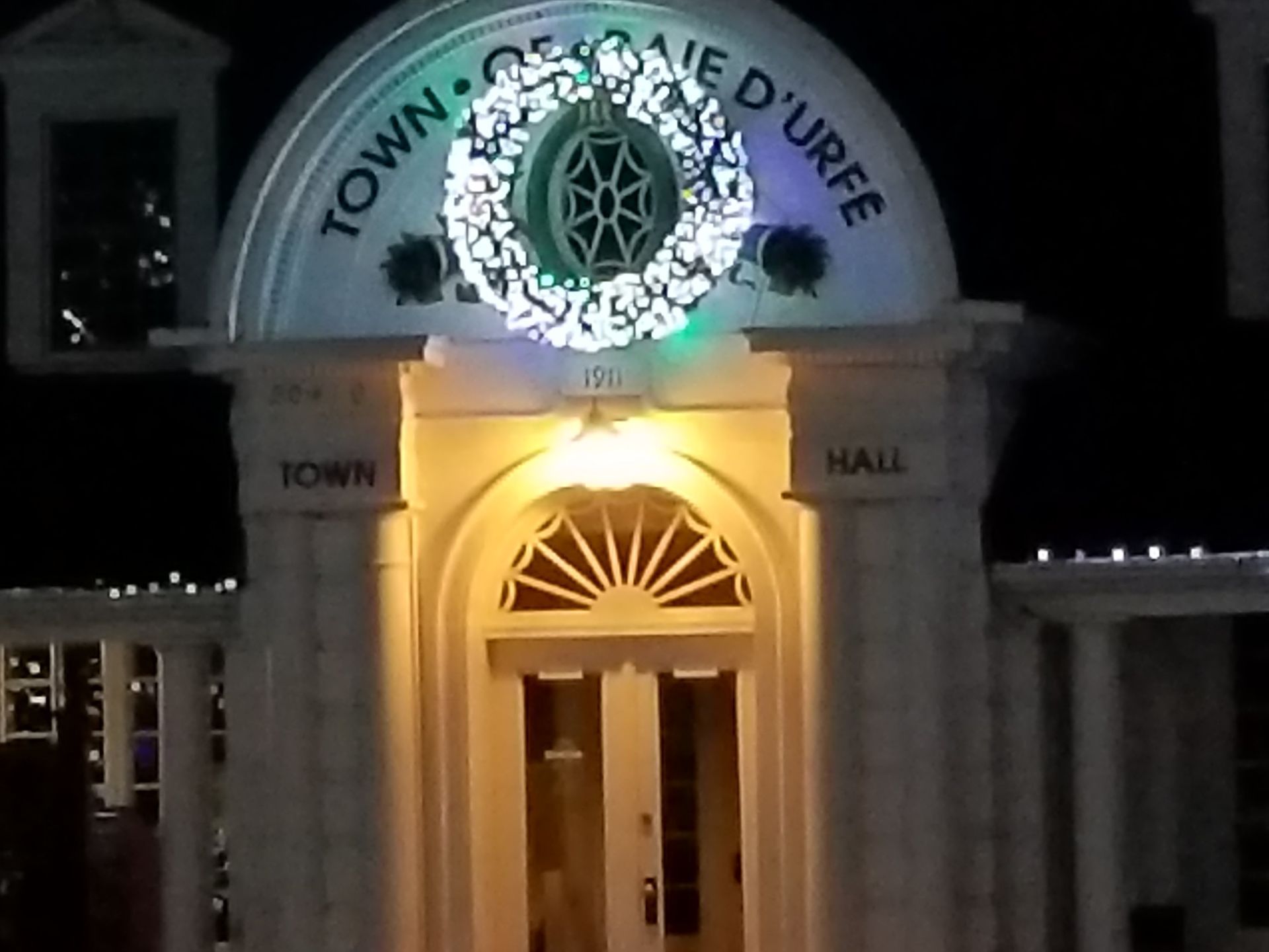 A white building with a christmas wreath on top of it