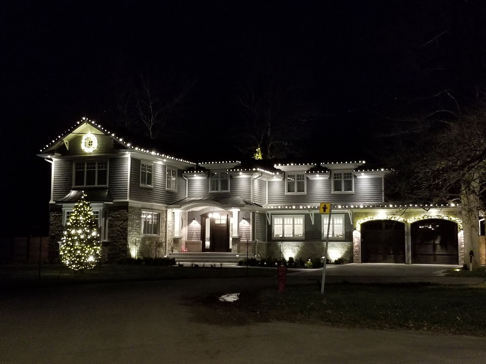 A large house is lit up with christmas lights at night.
