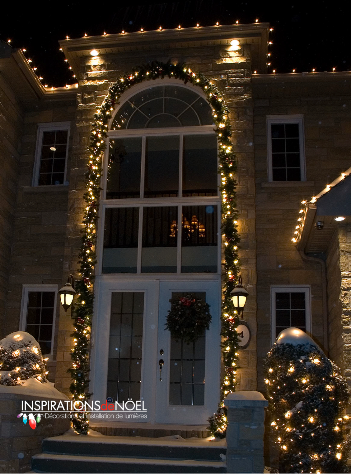 The front door of a house is decorated with christmas lights