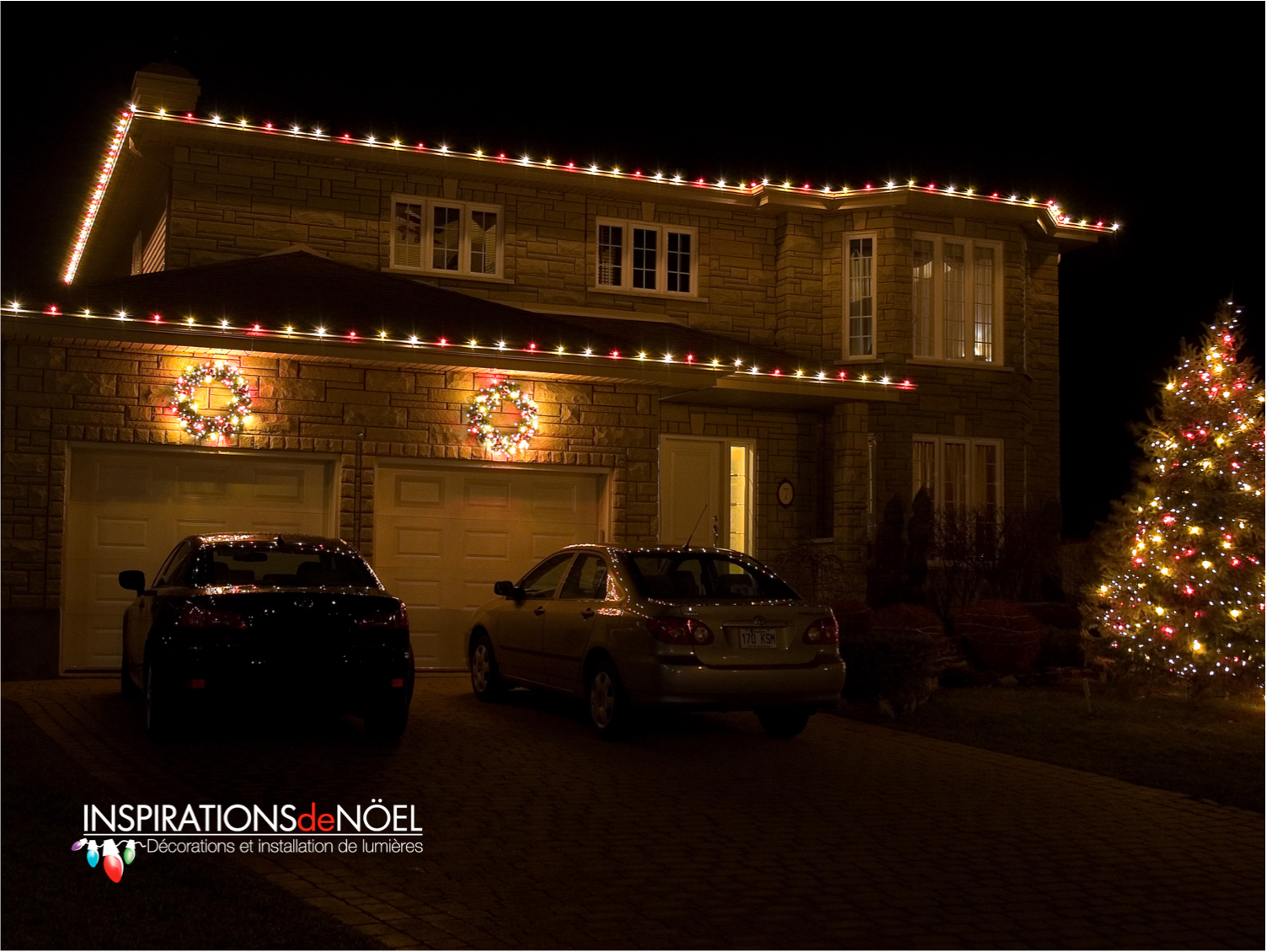 Two cars are parked in front of a house decorated for christmas