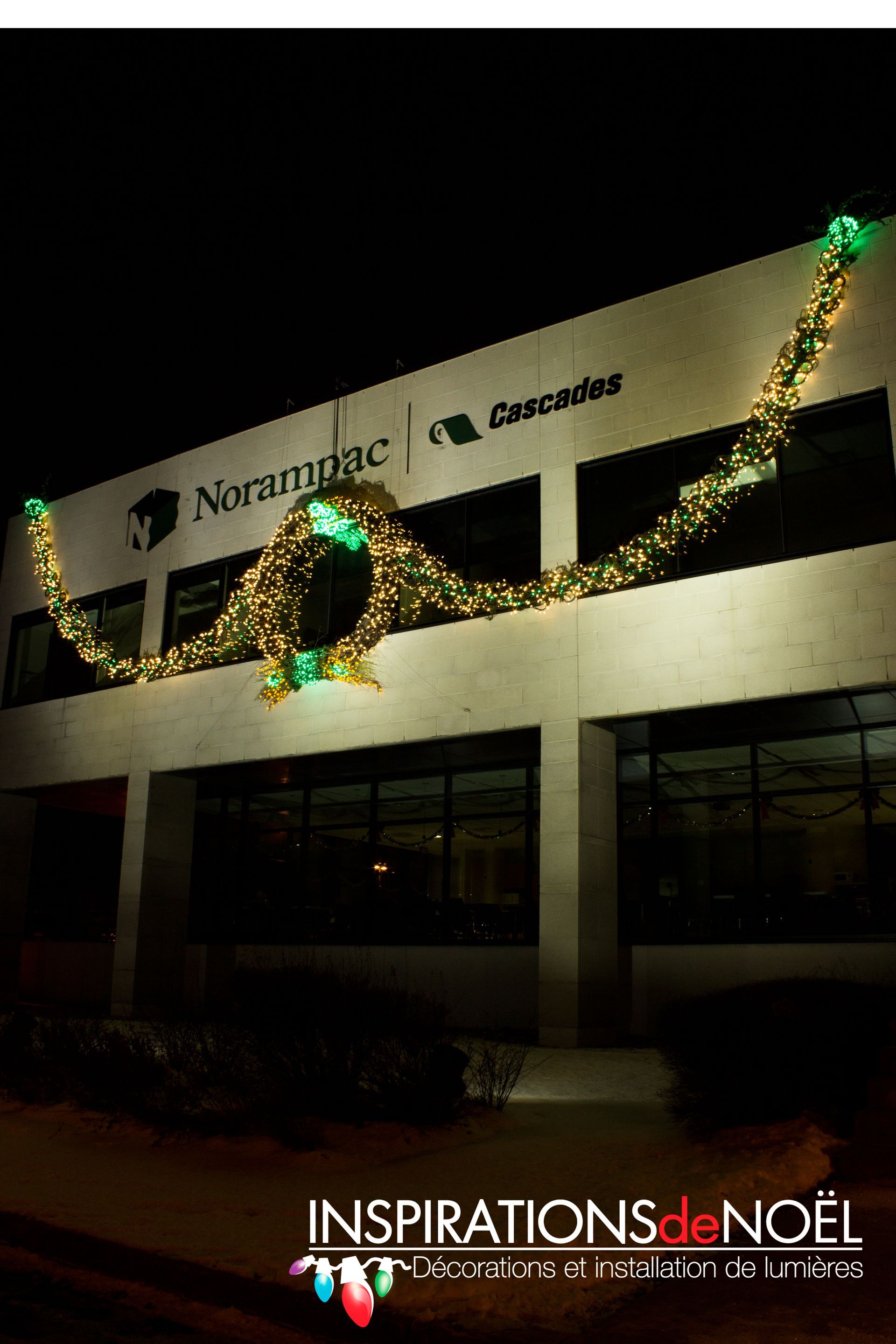 A large building with christmas lights on it is lit up at night.