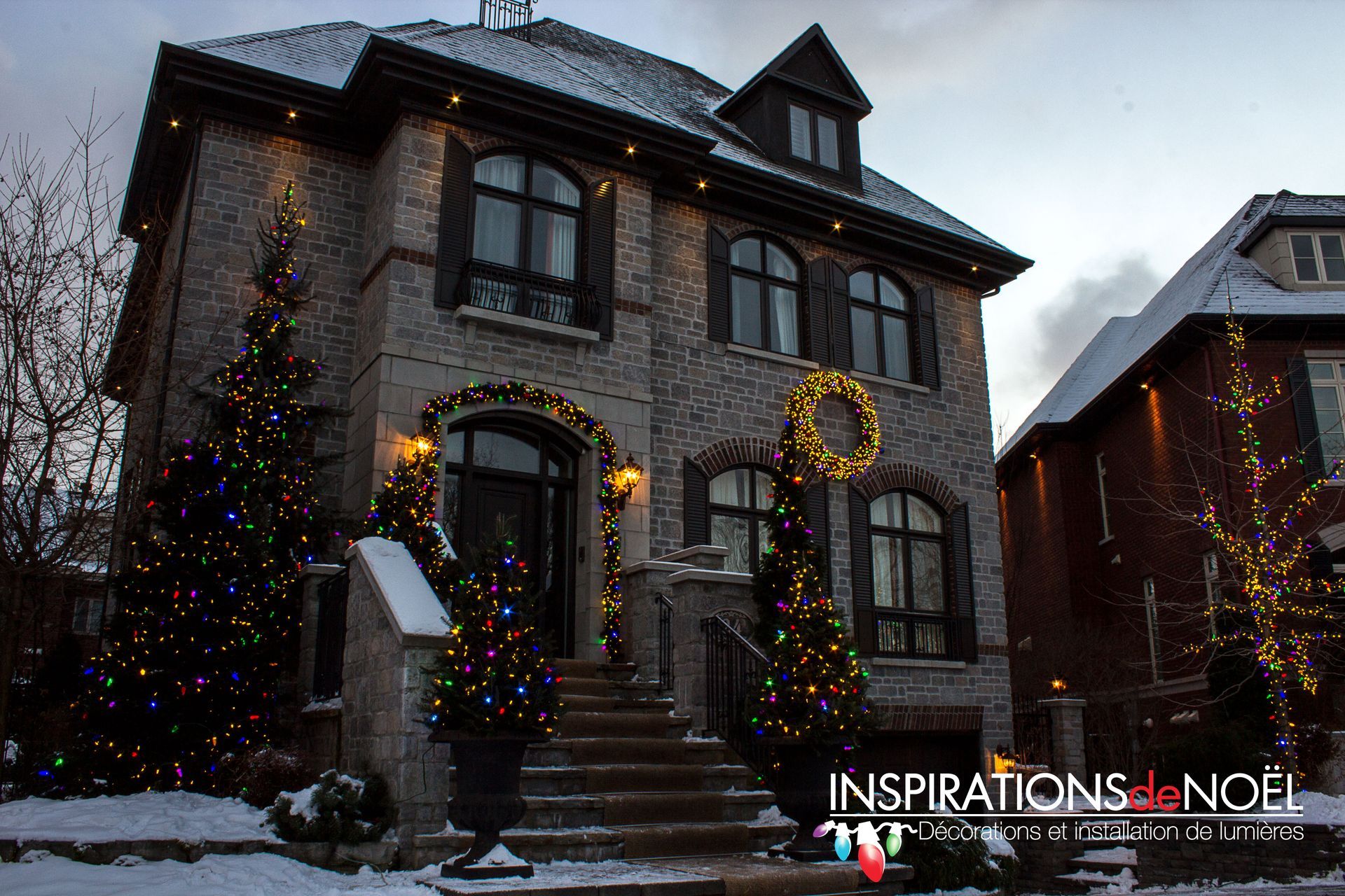 A large house is decorated with christmas lights and a wreath.
