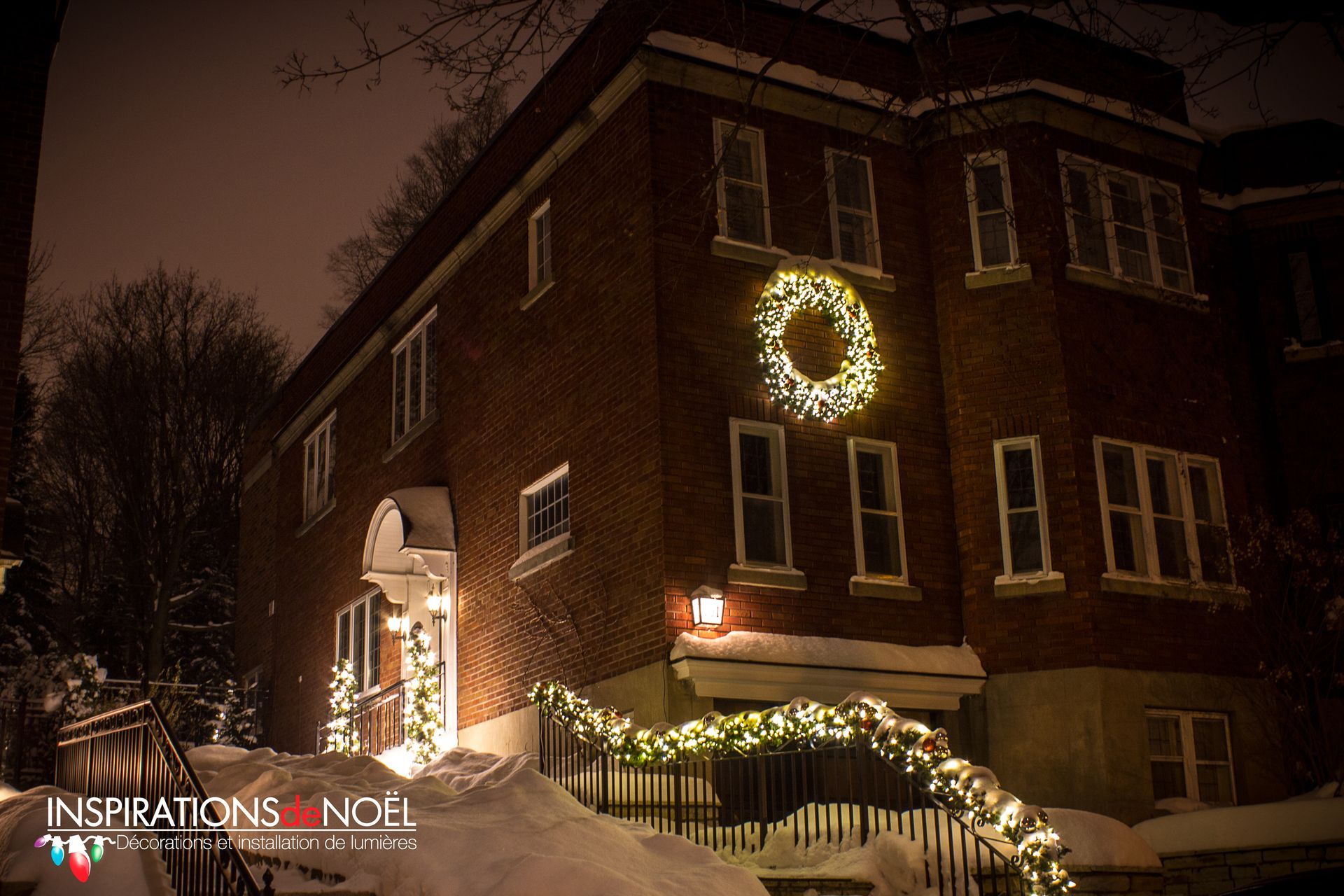 A large brick building is decorated with christmas lights and a wreath