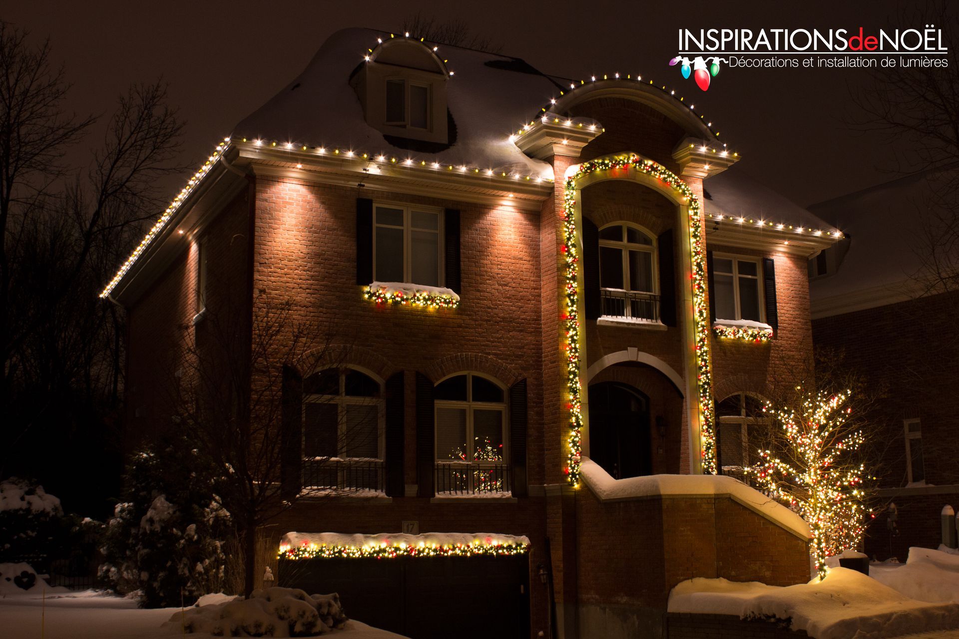 A large brick house is decorated with christmas lights