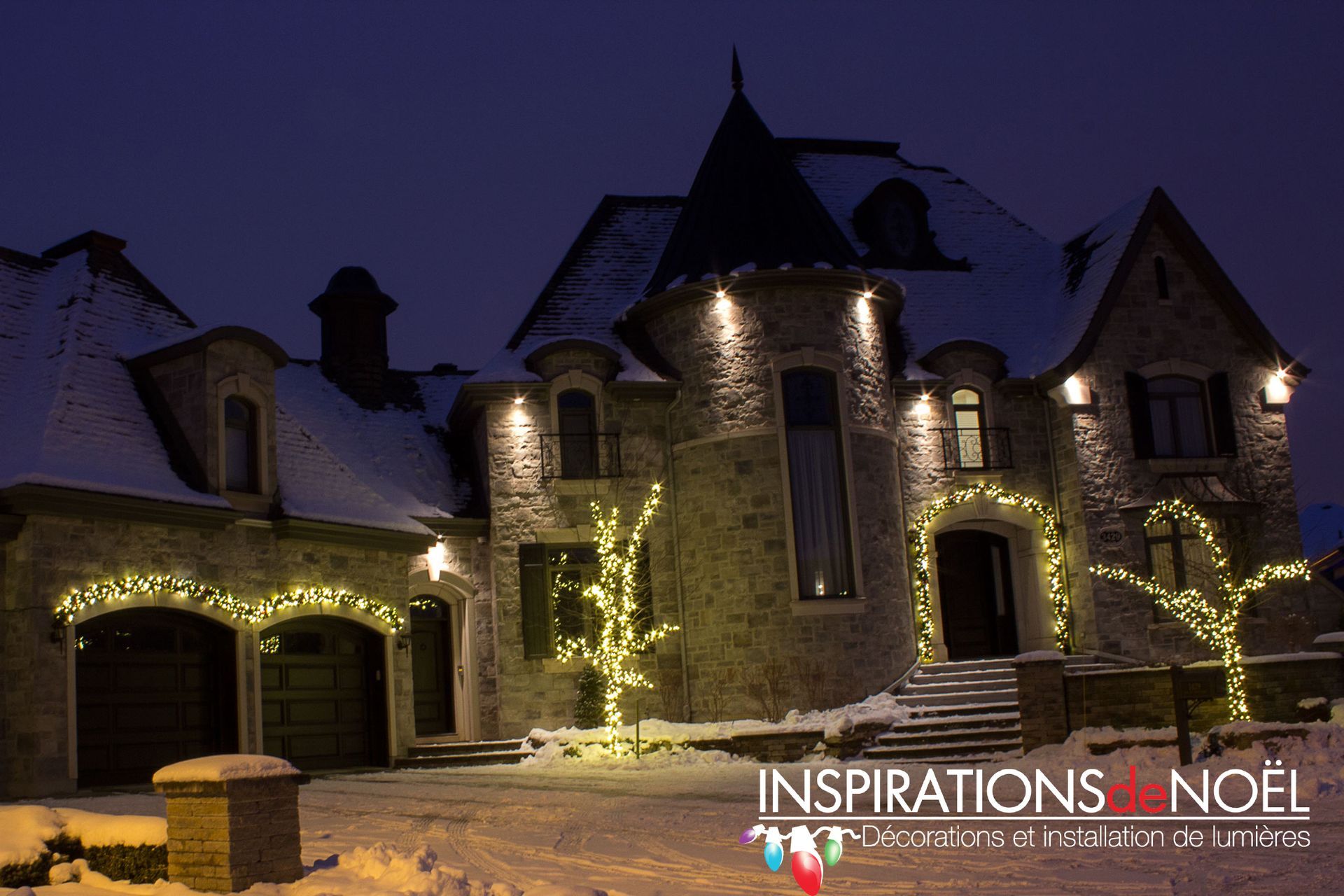 A large house is decorated with christmas lights at night.