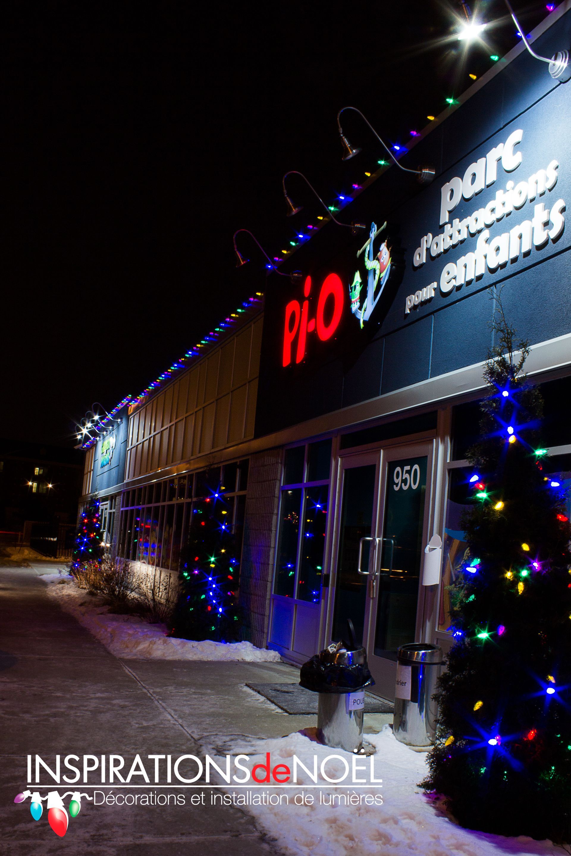 A building with christmas lights on it and a christmas tree in front of it