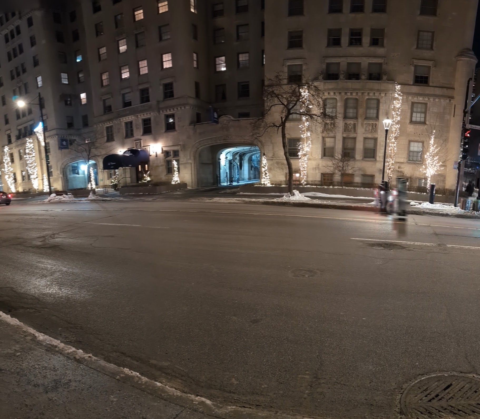 A busy intersection at night with a large building in the background