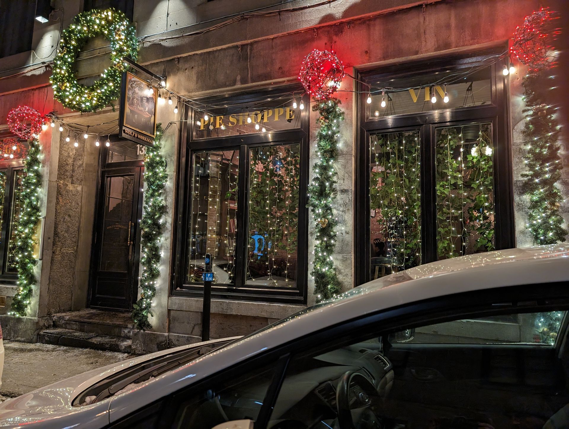 A car is parked in front of a building decorated for christmas.