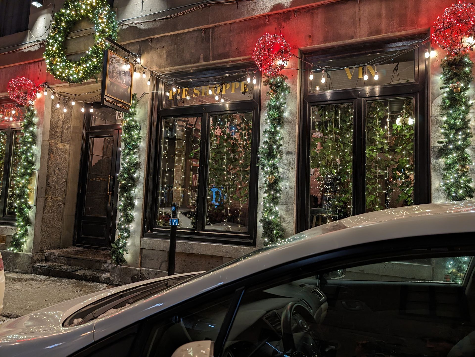 A car is parked in front of a building decorated for christmas.