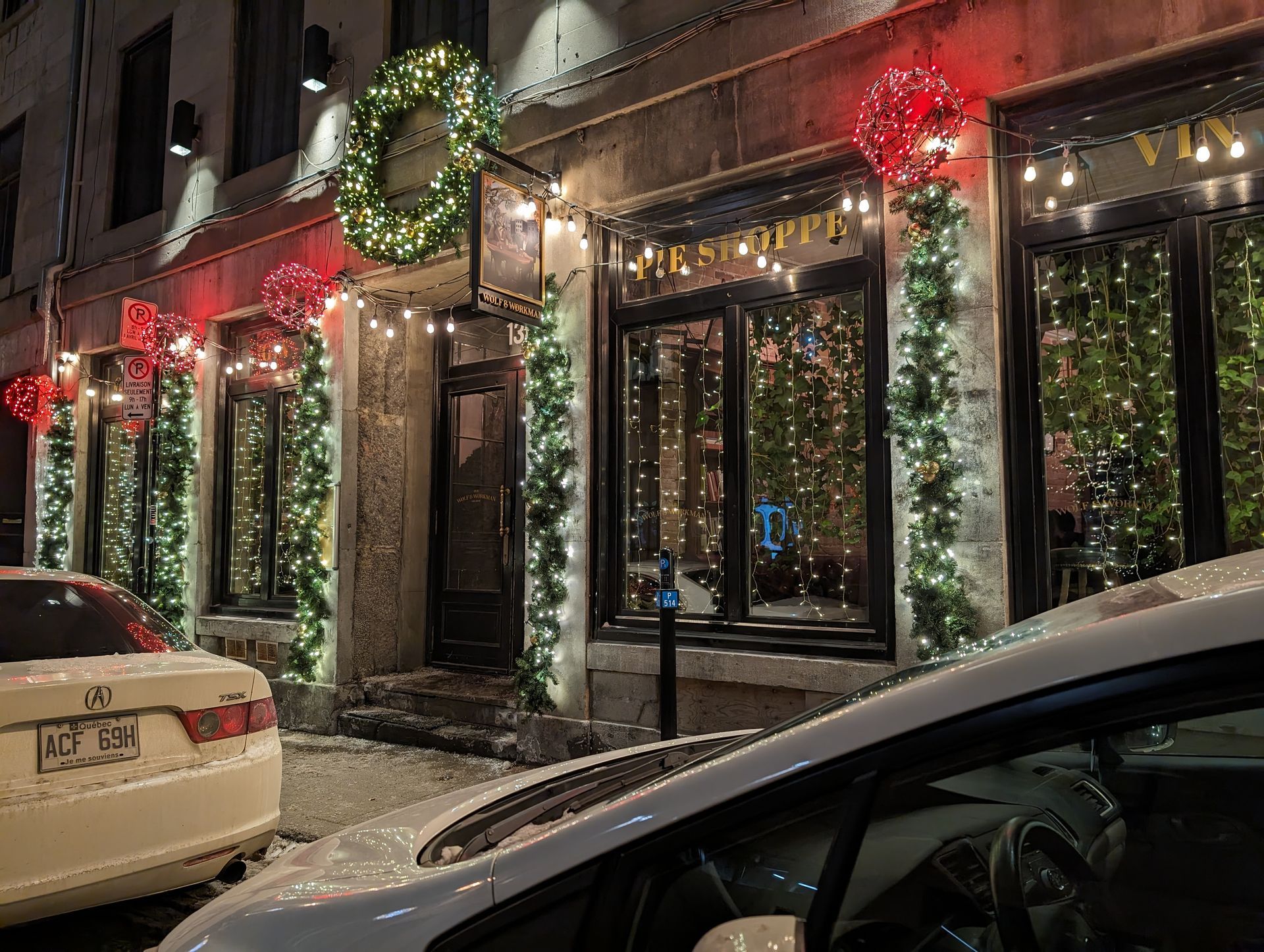 A white car is parked in front of a building decorated for christmas.