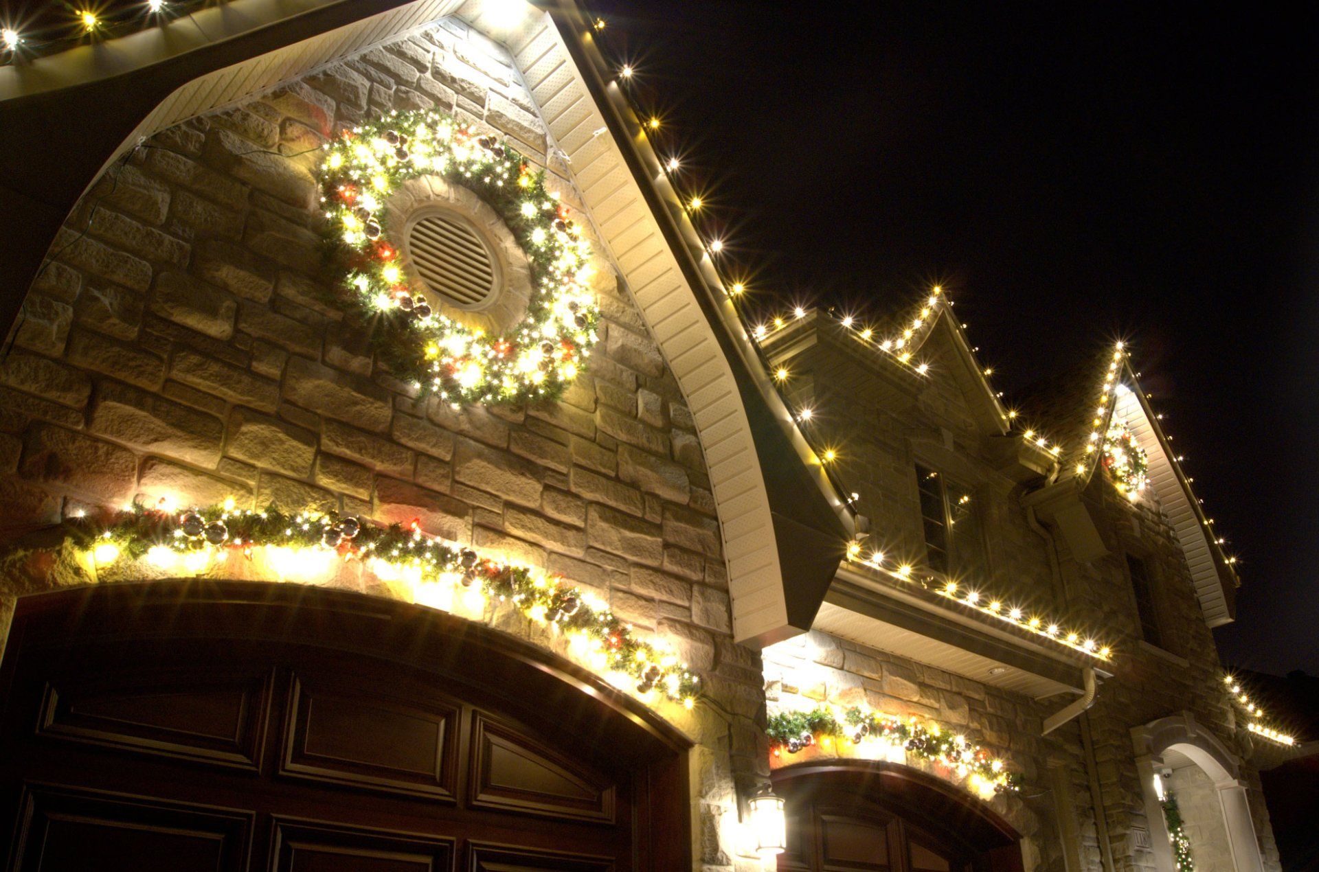 Une maison est décorée avec des lumières de Noël et une couronne.
