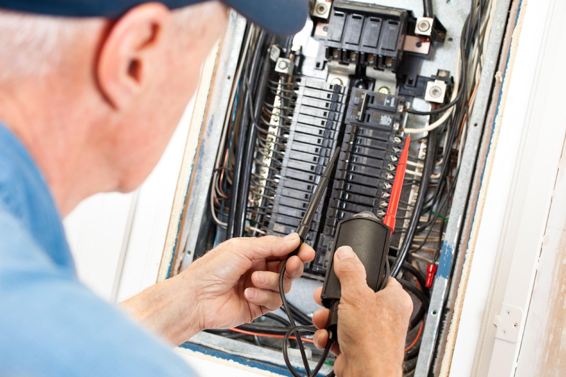 Electrician checking electrical panel with a multimeter.