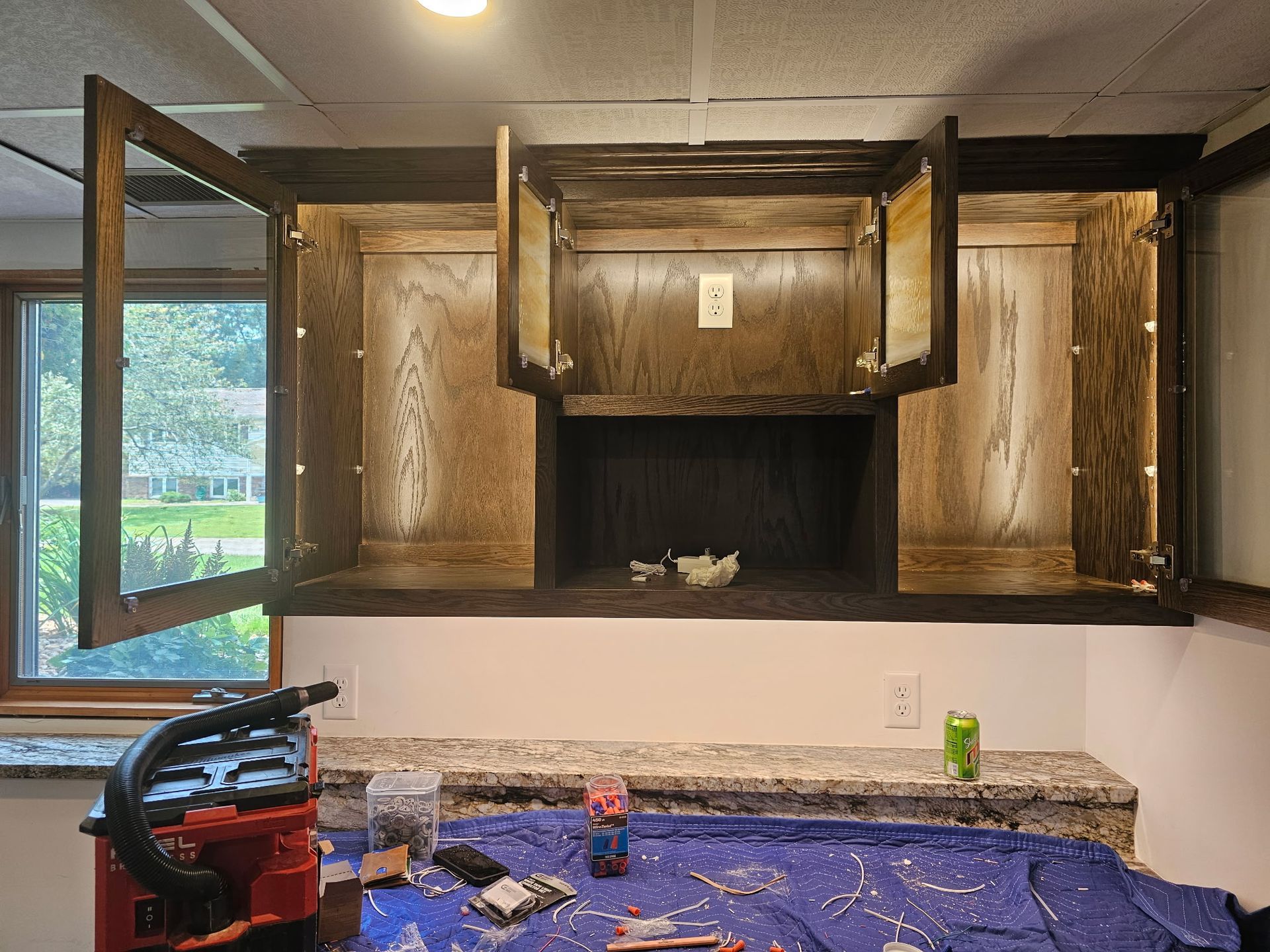 Upper kitchen cabinets with open doors, above a countertop and window.