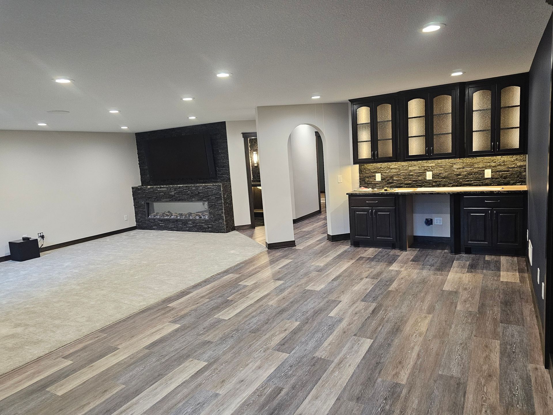 Spacious finished basement with fireplace, bar area, and hardwood floors.