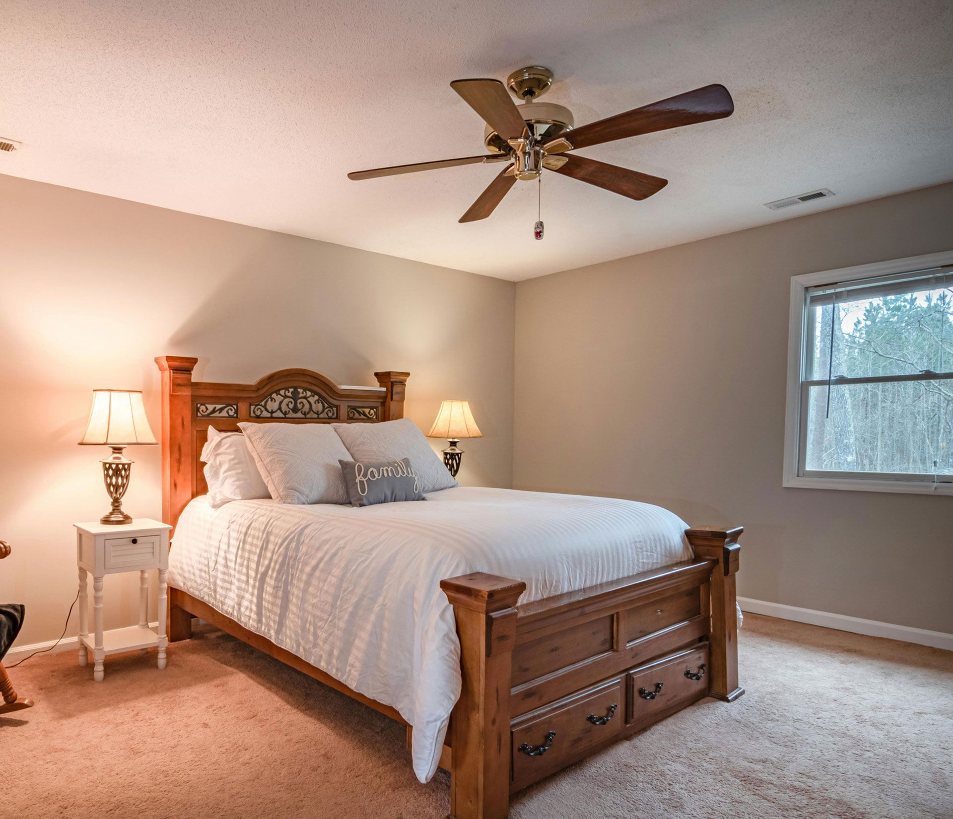 Bedroom with wooden bed, nightstands, lamps, and a ceiling fan.