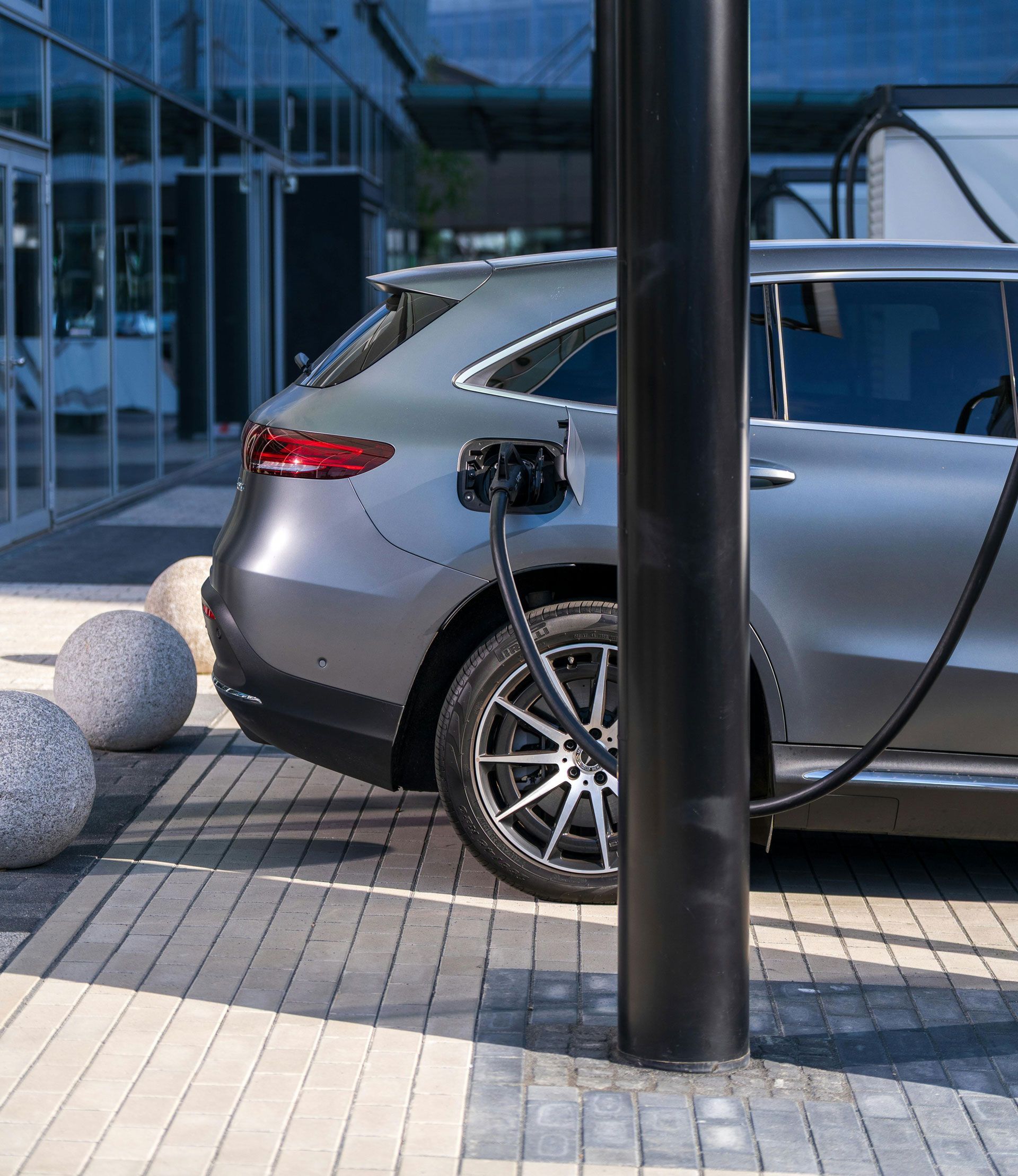 Gray electric SUV charging at a station.