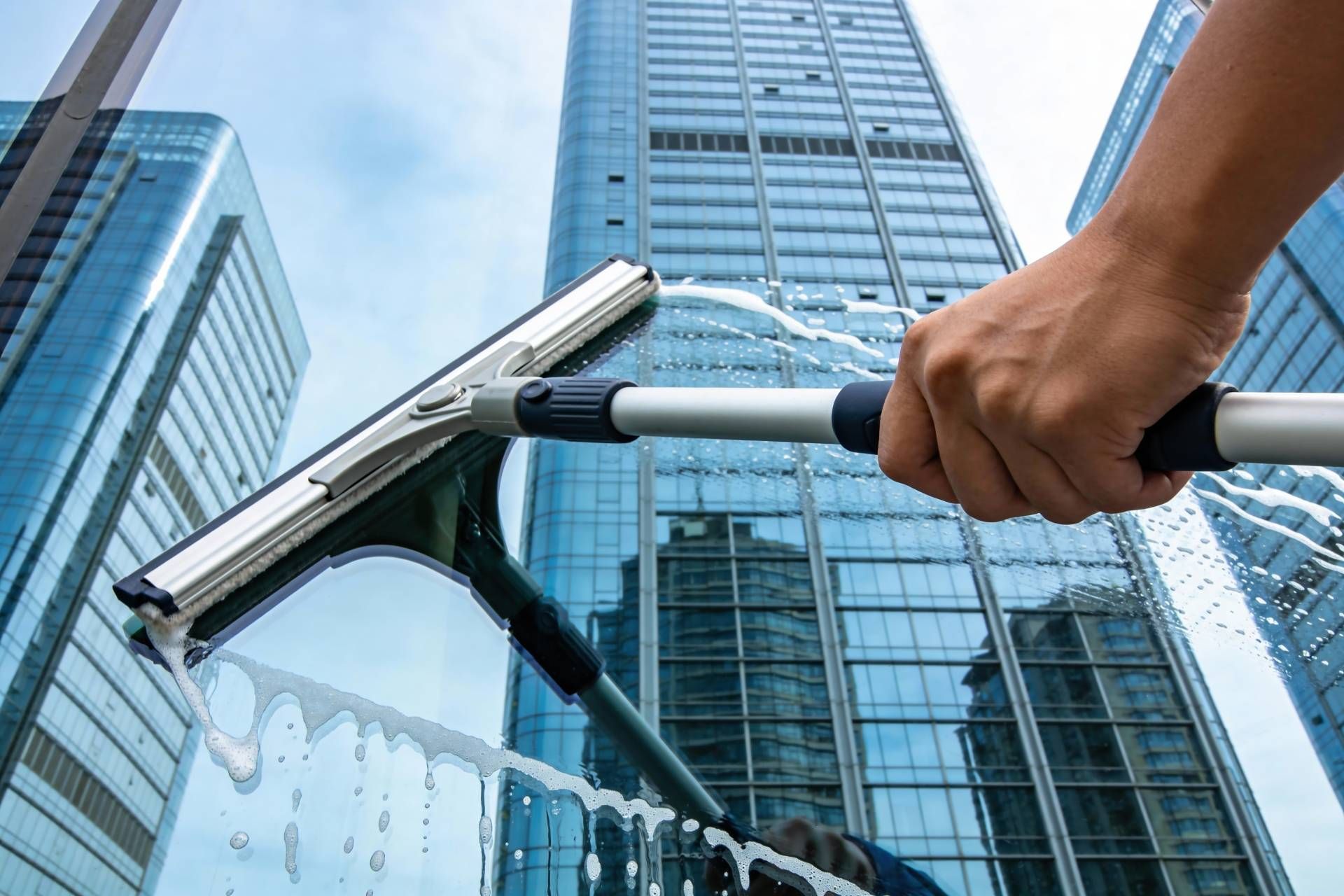 Window cleaner using a squeegee on a glass skyscraper facade