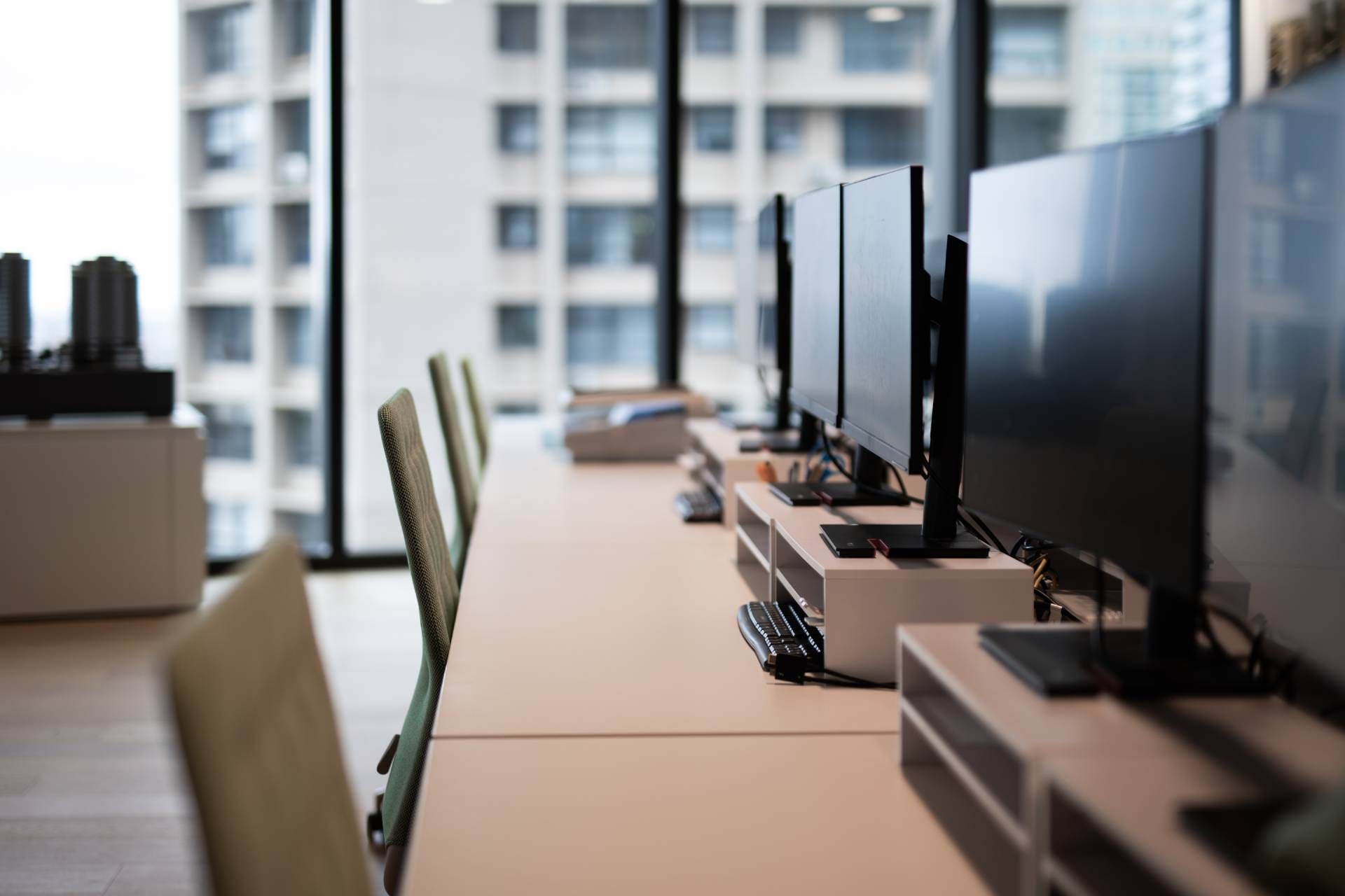 Empty modern computer lab with rows of desktop monitors and chairs by large windows.