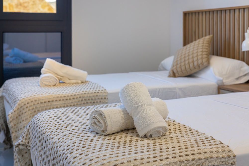 Two neatly made single beds with folded white towels in a bright hotel room