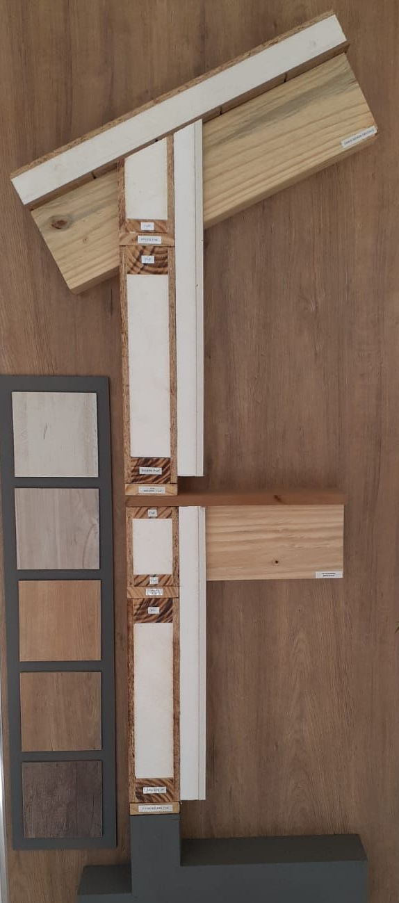 Expositor de sección transversal estructural de madera con muestras de color y logotipo, montado en una pared.