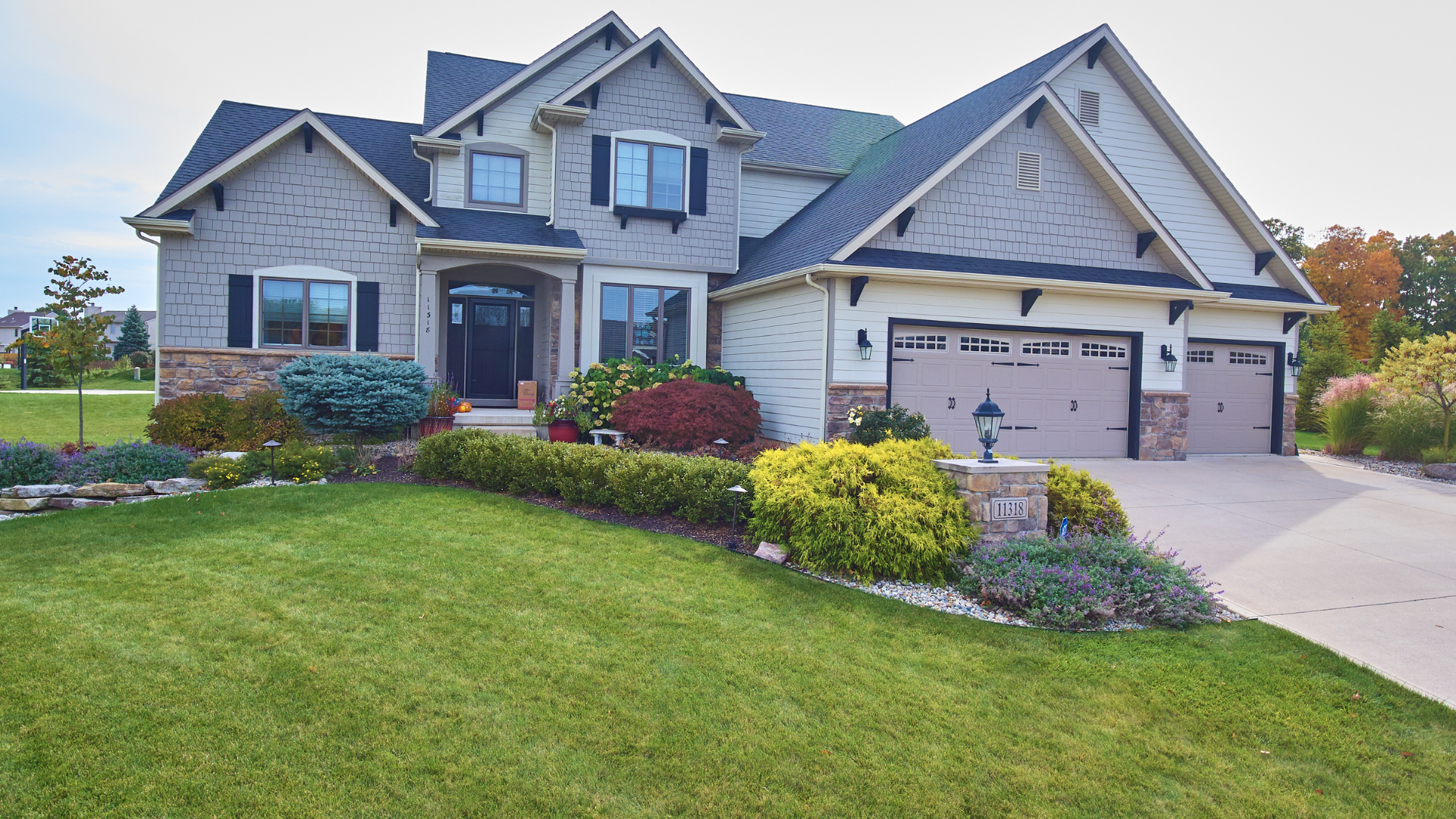 A large brick house with two garages and a lush green lawn.