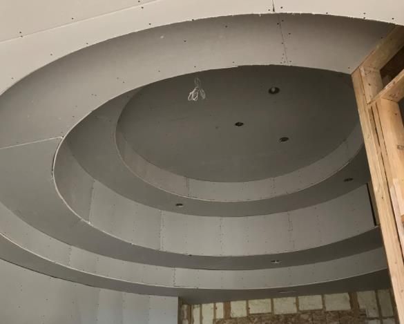 Circular drywall ceiling design under construction with recessed lighting.