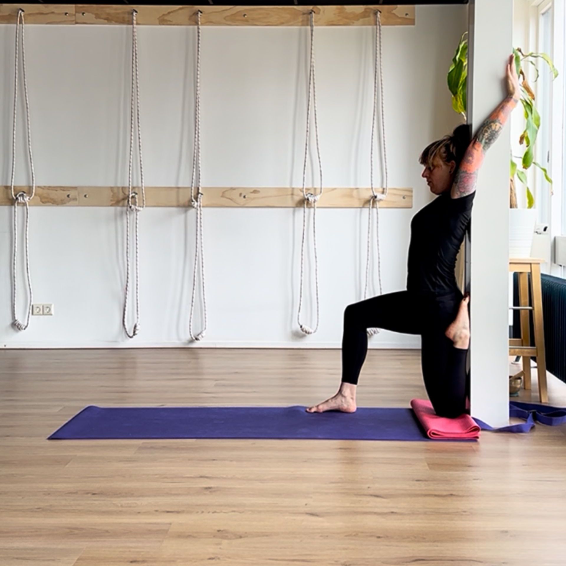 Eka pada rajakapotasana, een gevorderde yogahouding, met steun van een pilaar – in de yogastudio in Tuinzigt, Breda