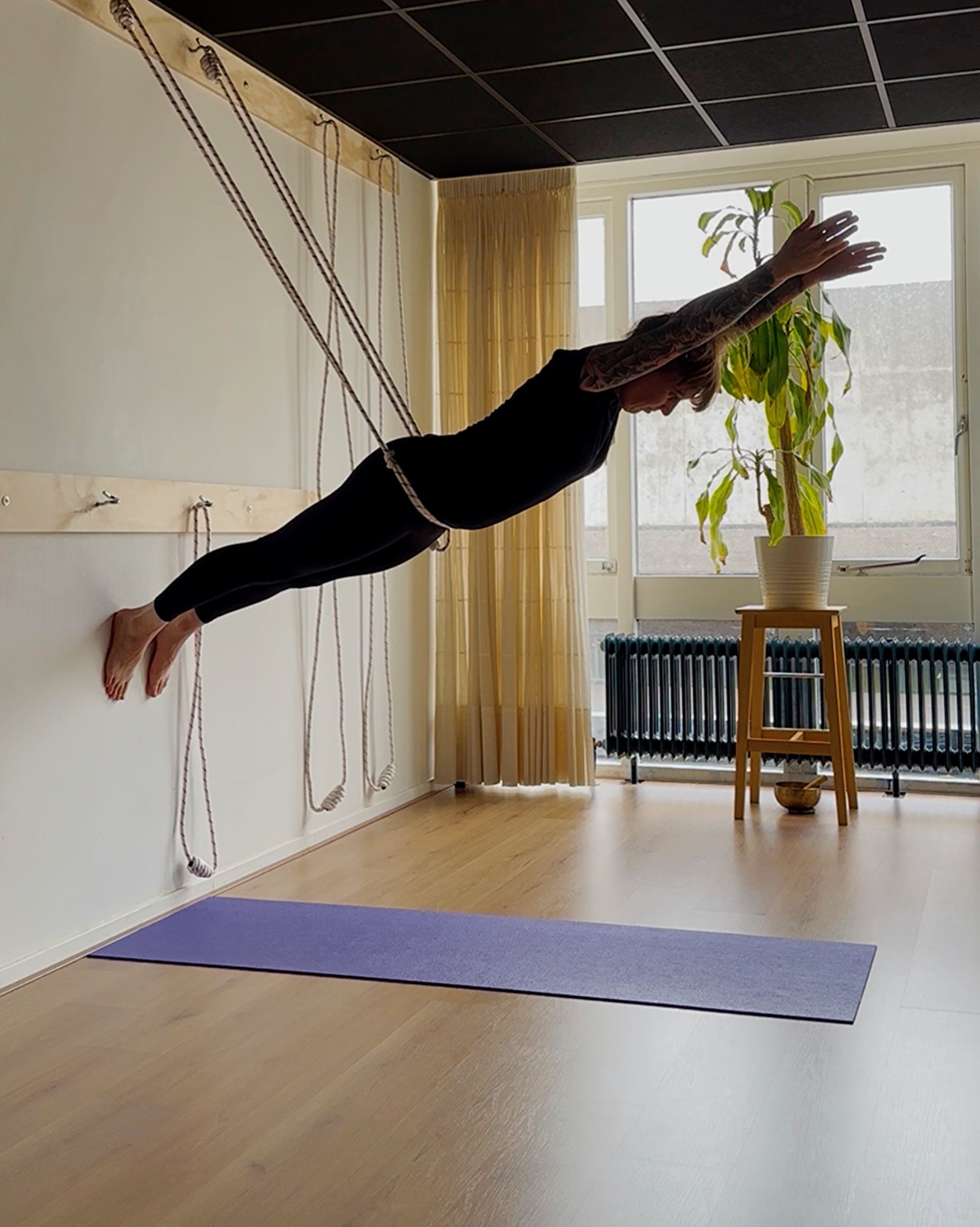 Een speelse  variant van de supermanhouding in de touwen in de yogastudio.