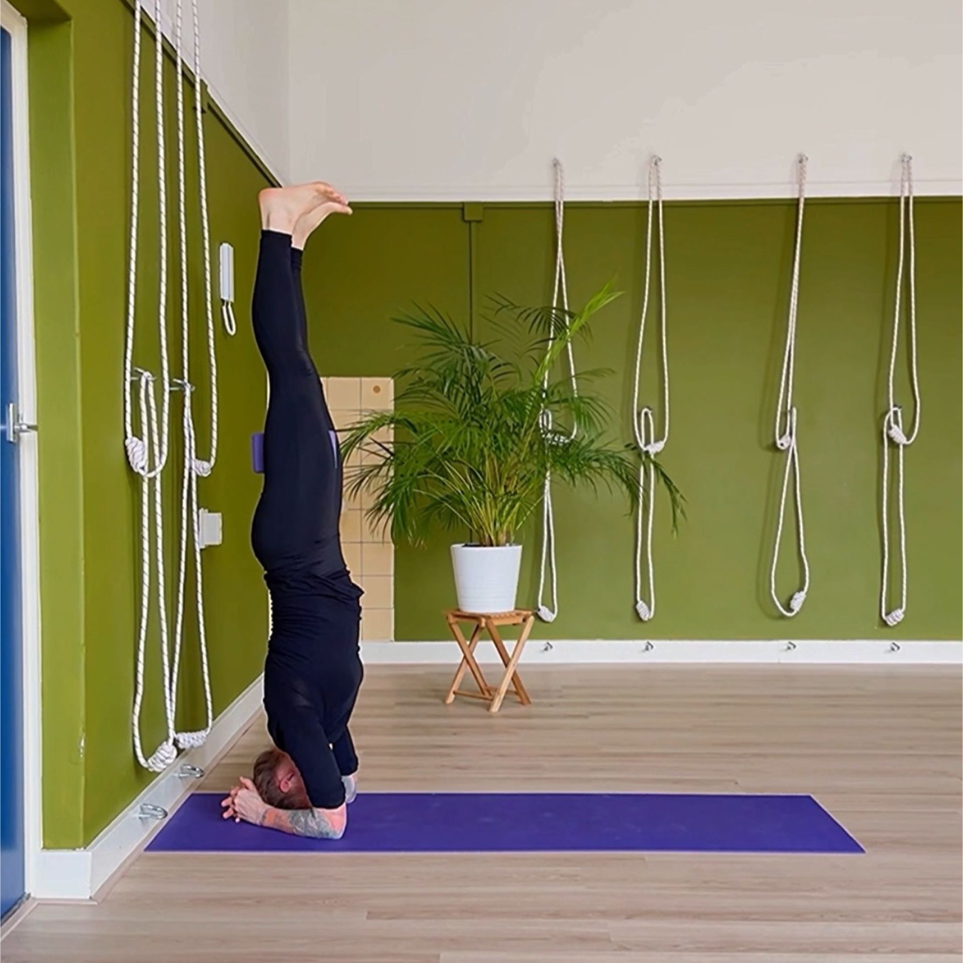 Kopstand met een yogablok tussen de dijbenen. Los of tegen de muur.