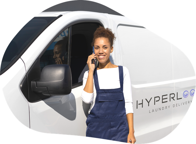 Woman in blue overalls on phone, standing near a white van with