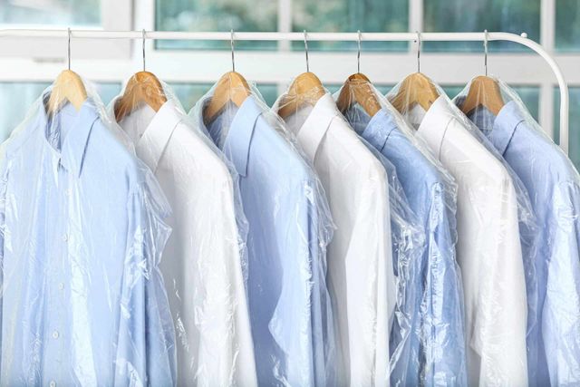 Shirts on hangers, in protective plastic, at a dry cleaner. Mostly blue and white.