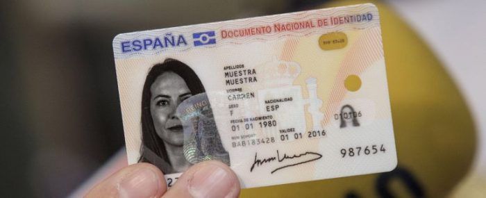 Una mujer sostiene un documento de identidad español en su mano.