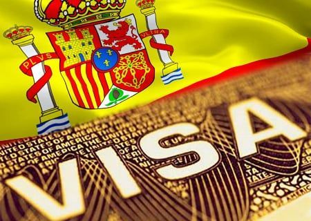 Un primer plano de una visa con una bandera española al fondo.