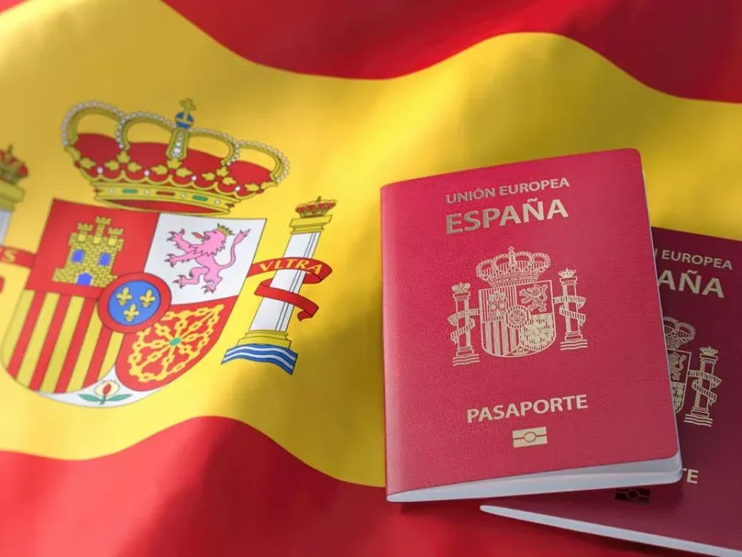 Dos pasaportes españoles están sentados frente a una bandera española.