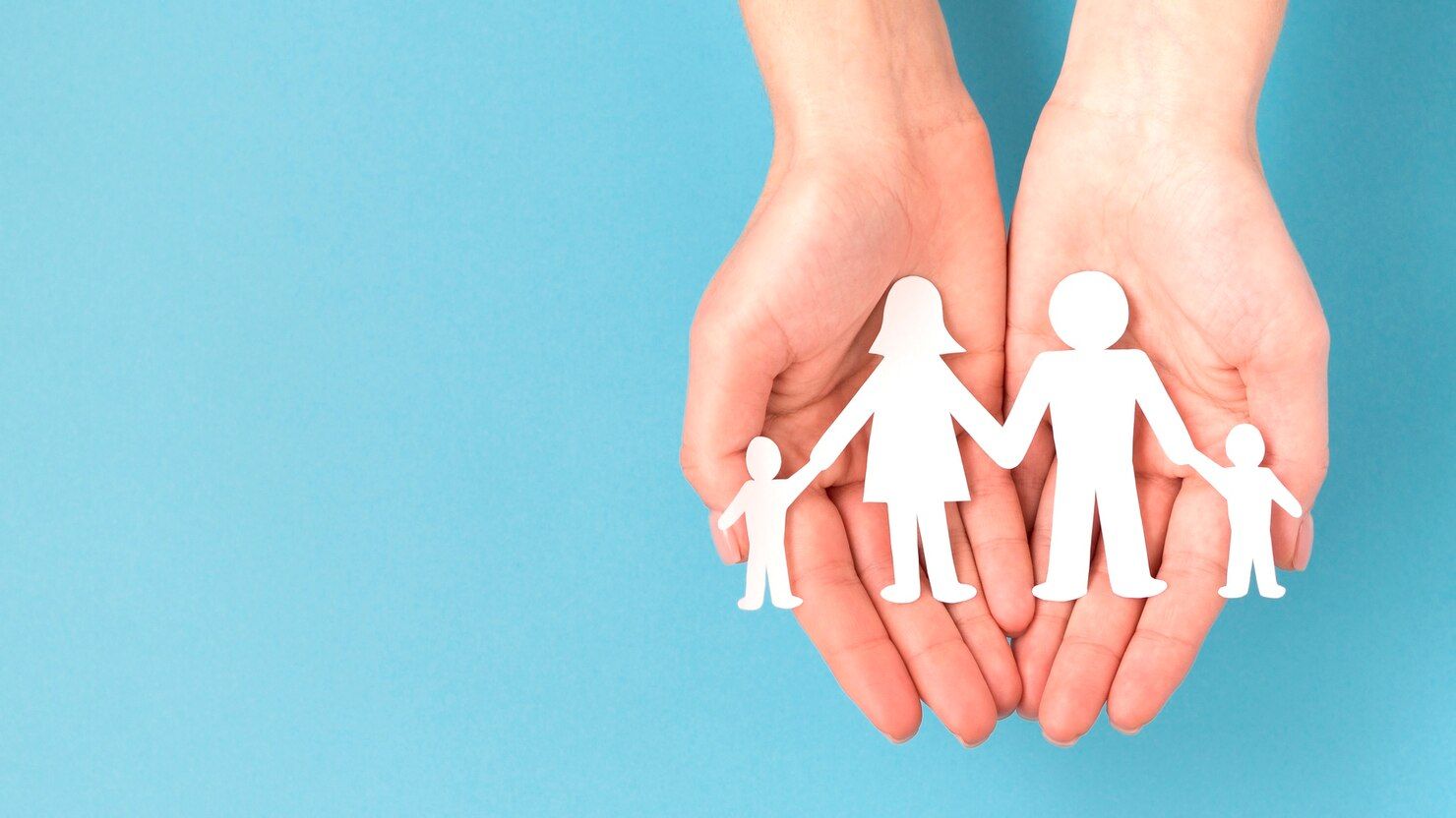 Una persona sostiene un recorte de papel de una familia.