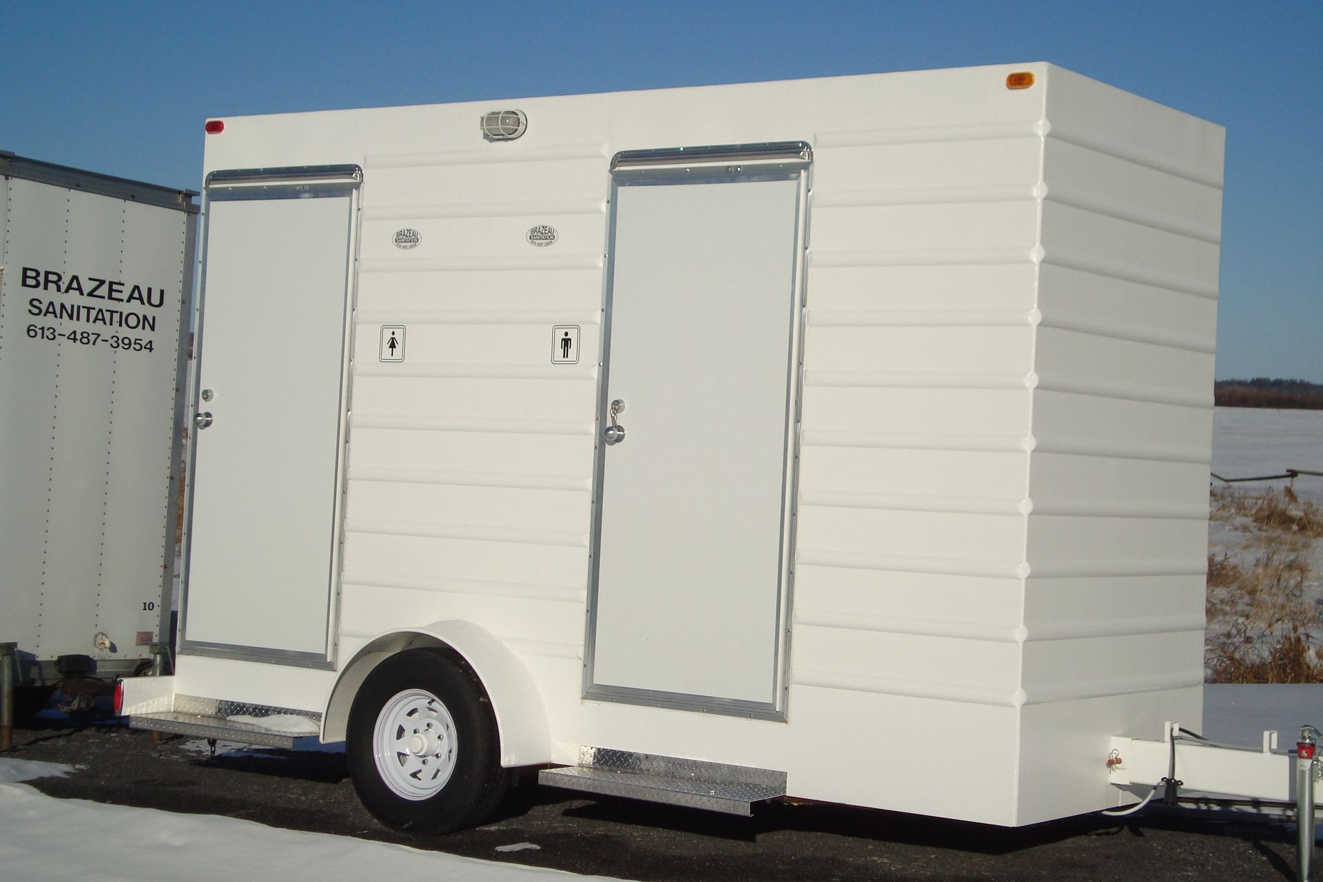 A white trailer toilets. Brazeau Sanitation