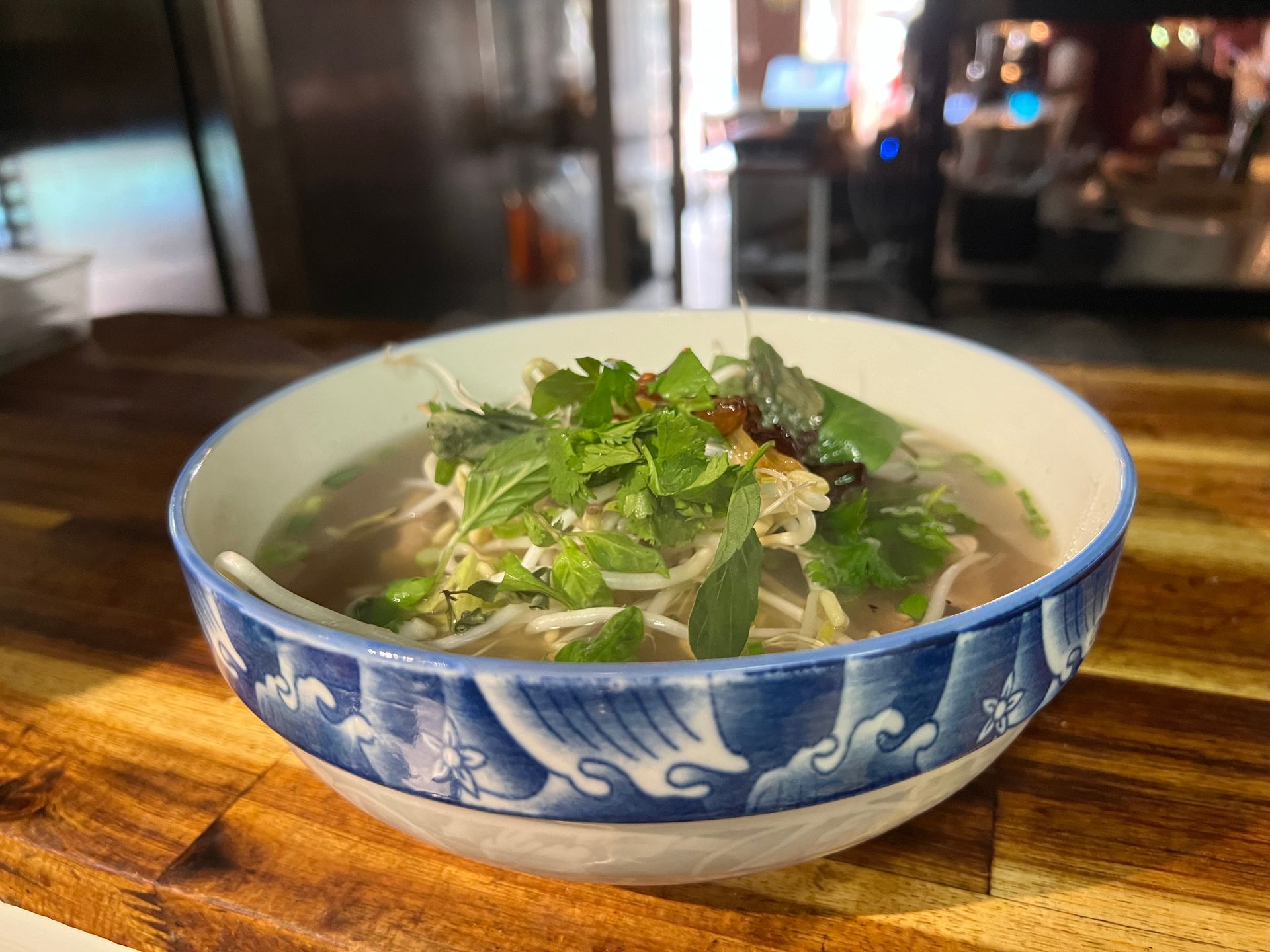 A bowl of soup is sitting on a wooden table.
