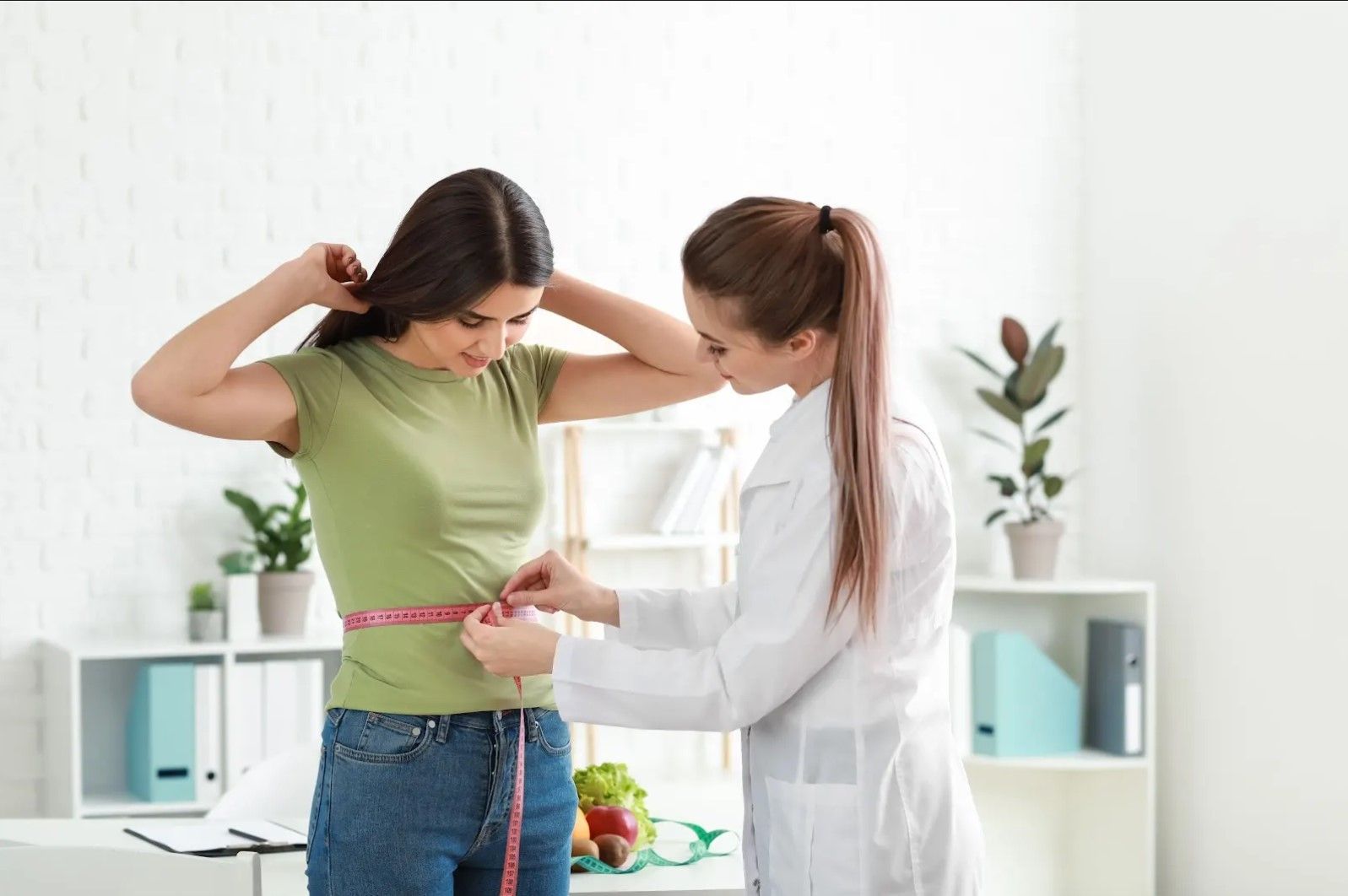 A woman is being measured by a doctor with a tape measure.