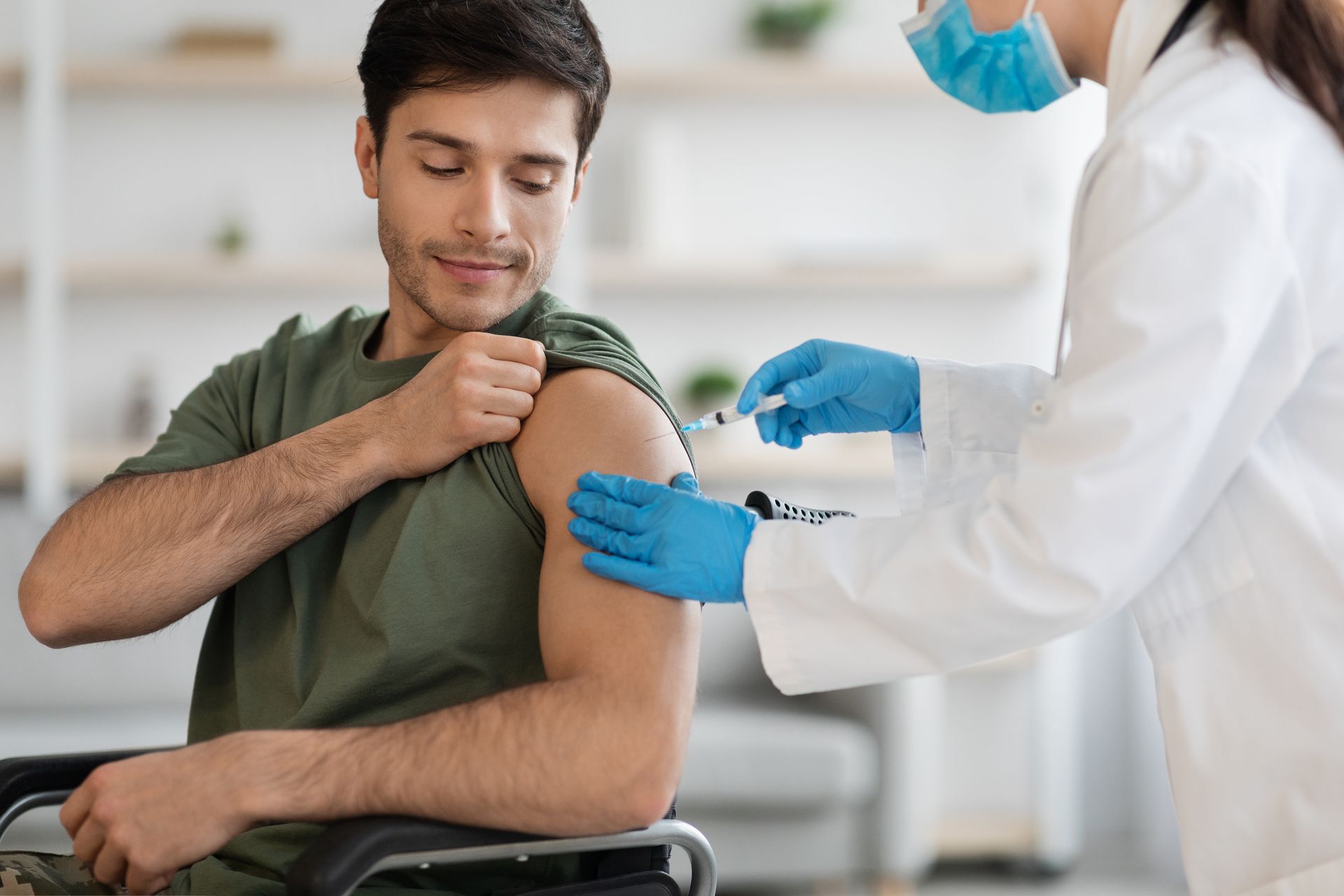 A man in a wheelchair is getting an injection from a doctor.