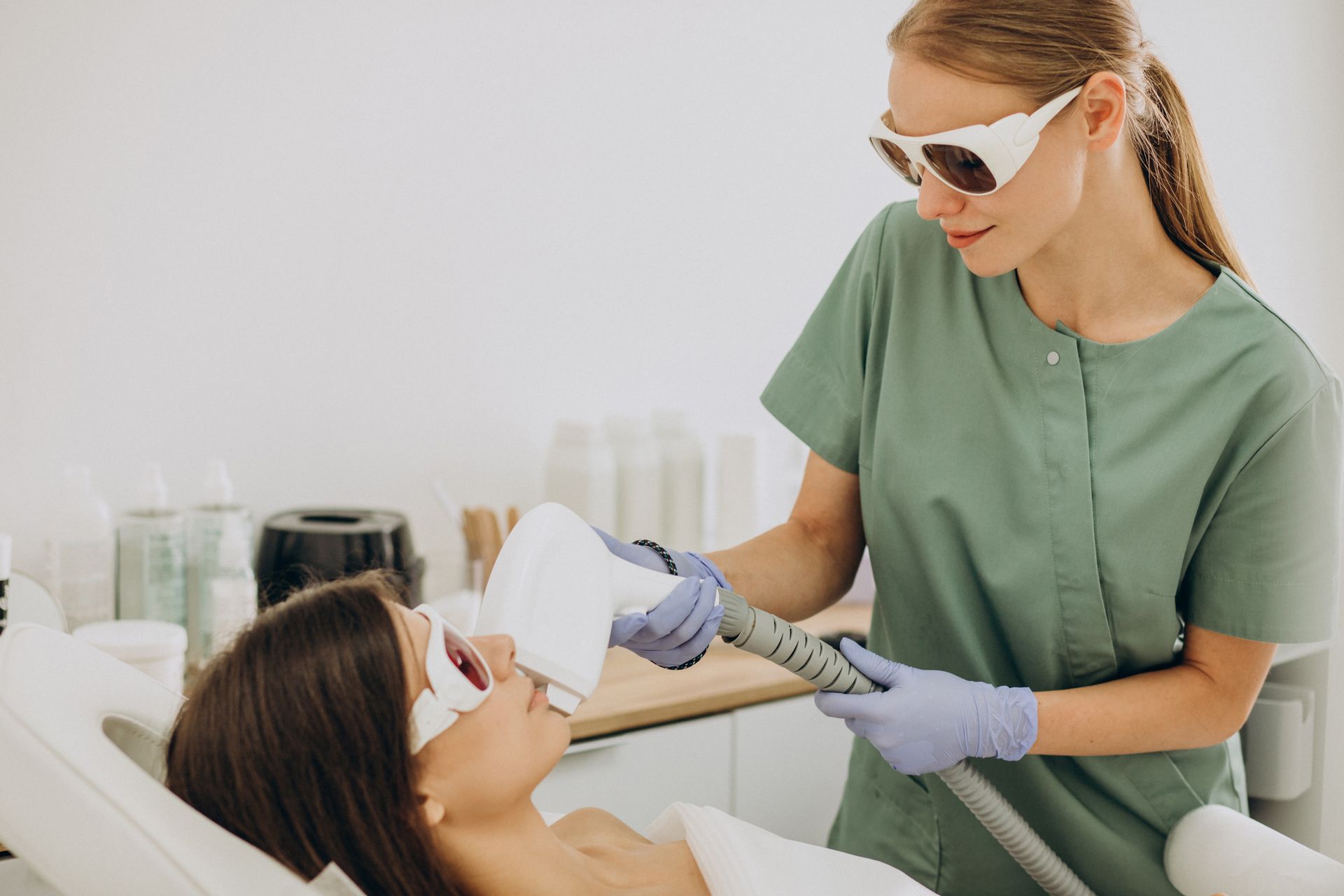 Woman receiving laser hair removal treatment on face. Doctor in gloves and goggles operating device.